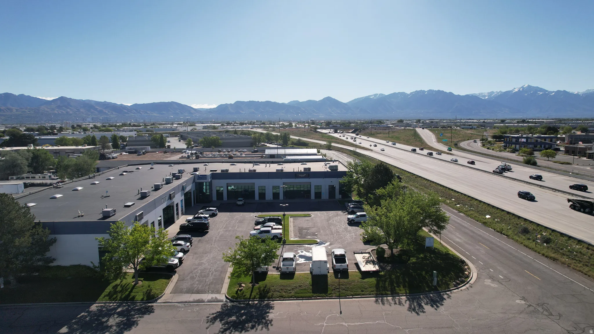 Industrial building with a substantial parking area, situated directly alongside a multi-lane highway