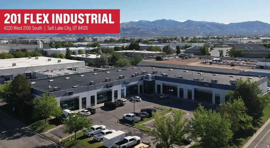 Industrial flex building featuring a dark flat roof, multiple large bay doors, and extensive paved parking areas