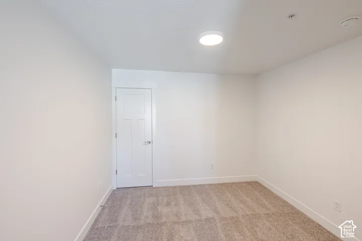 Neutral tone wall finishes, white trim, recessed ceiling light, paneled door, and carpet flooring