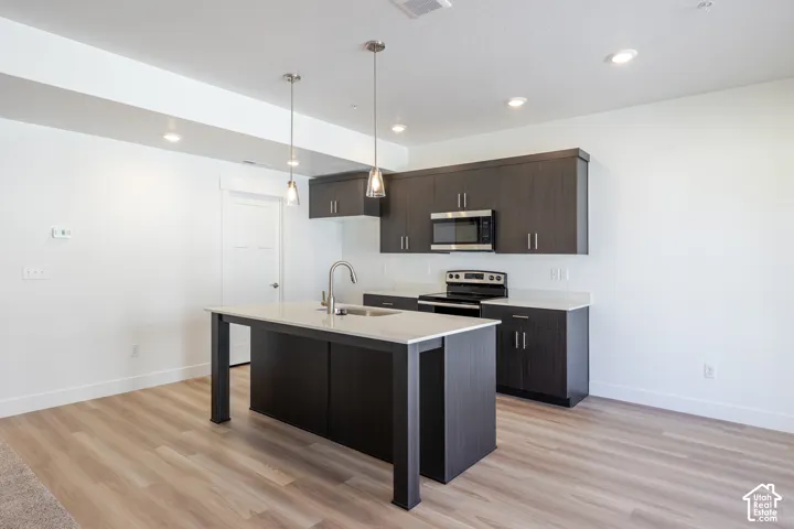 Wood-finish flooring, recessed lighting, and a kitchen island with pendant lighting
