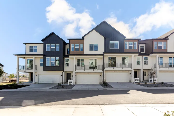 Contemporary multi-story architecture with attached garages, balconies featuring black railings, and a clean exterior palette