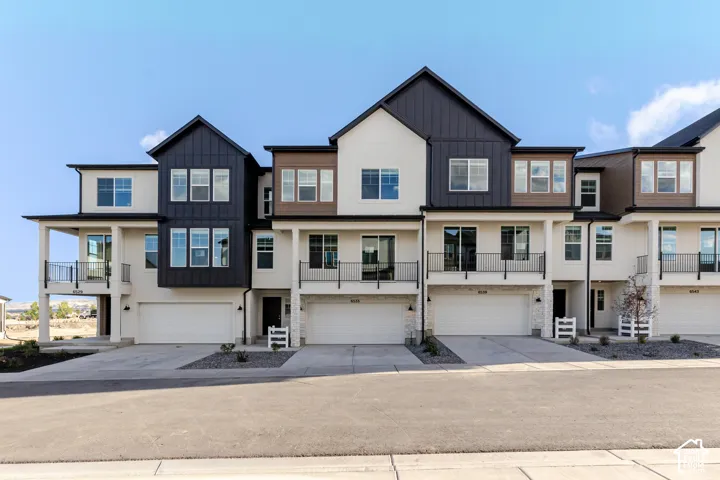 Modern townhome exterior featuring a clean-lined facade, dark accent siding, and private balconies with black railings