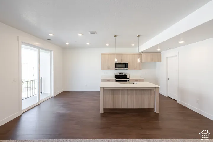 Open-concept living area featuring wood-finish flooring, recessed lighting, and a sliding glass door to a balcony
