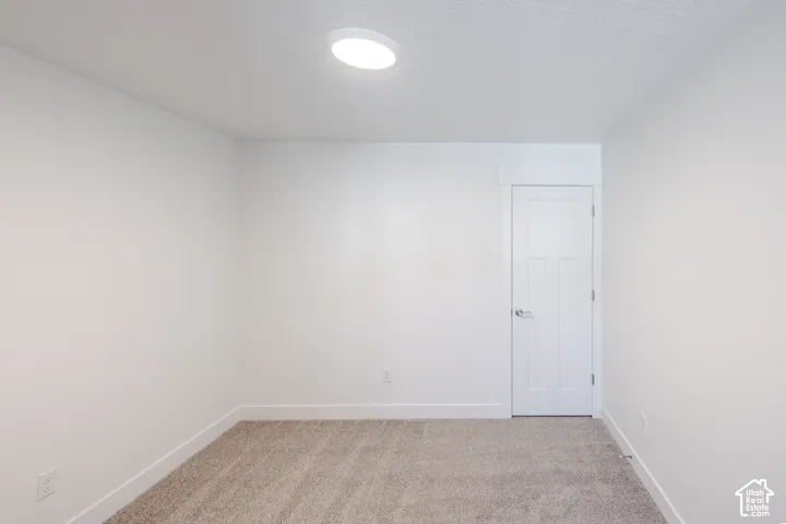Neutral-toned carpeting, white walls, and a contemporary flush-mount ceiling light