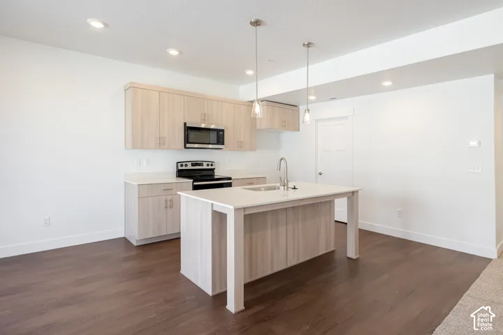 Contemporary kitchen featuring wood-finish cabinetry, light-toned countertops, and stainless steel appliances