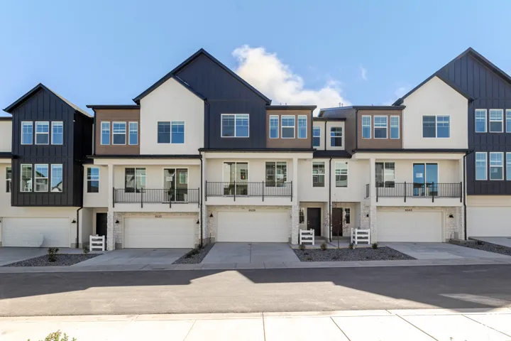 Modern townhome exteriors featuring white stucco, dark vertical siding, and wood-toned accents