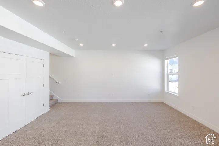 Recessed lighting illuminates this carpeted room with a single window