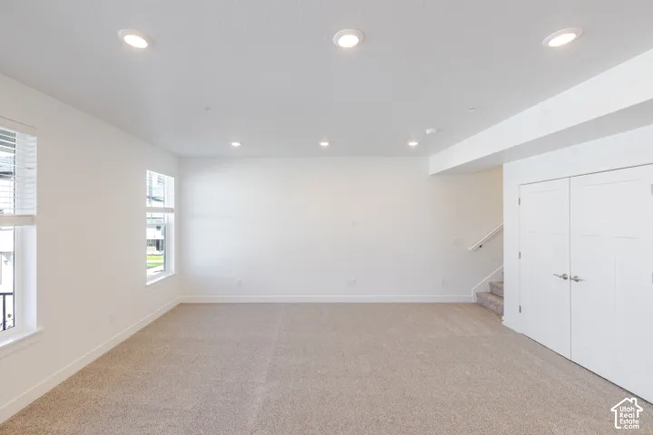 Neutral-toned interior space featuring recessed ceiling lighting, wall-to-wall carpeting, white walls, double-door closet cabinetry, and windows with white blinds