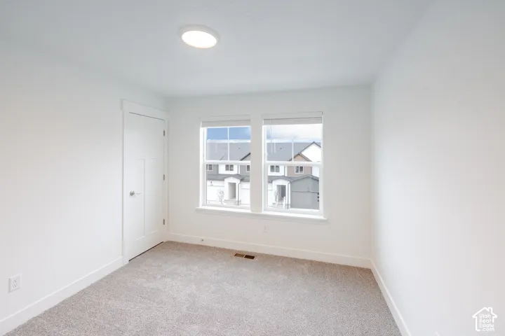Neutral-toned carpeting, two dual-pane windows with grid detailing, and a single-panel interior door with matching trim