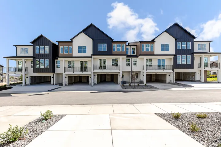 Modern townhomes featuring a multi-tone exterior, black metal railings, and integrated ground-level garage access