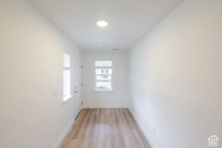 Neutral interior space featuring wood-finish flooring, two windows with blinds, and flush-mount ceiling lighting
