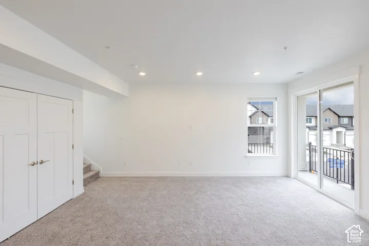 Interior space featuring neutral carpeting, recessed ceiling lighting, a white double-door closet, a single-pane window, and glass sliding doors providing external access