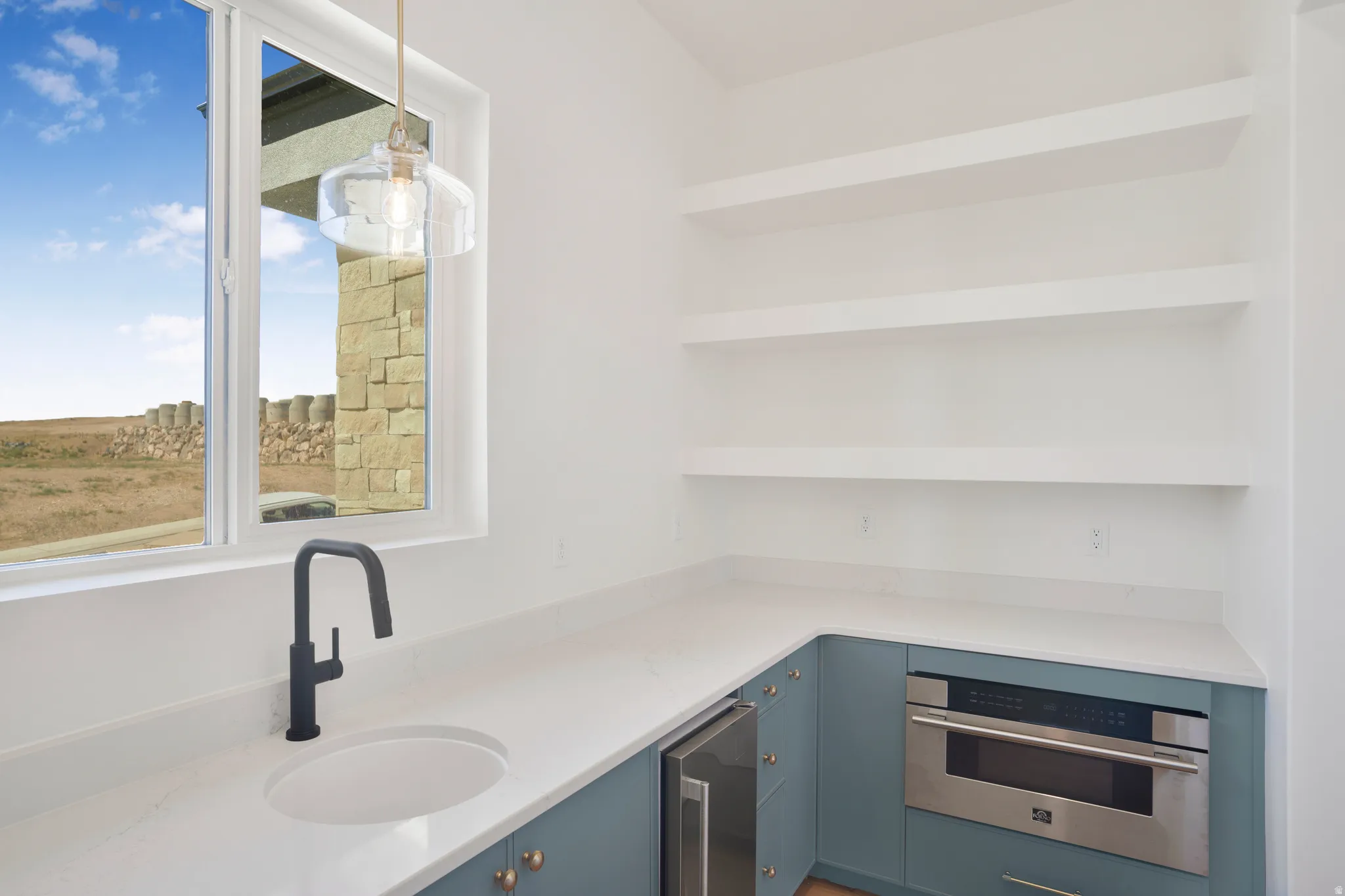 Kitchenette featuring a built-in microwave, integrated beverage cooler, and a single basin sink with a matte black faucet
