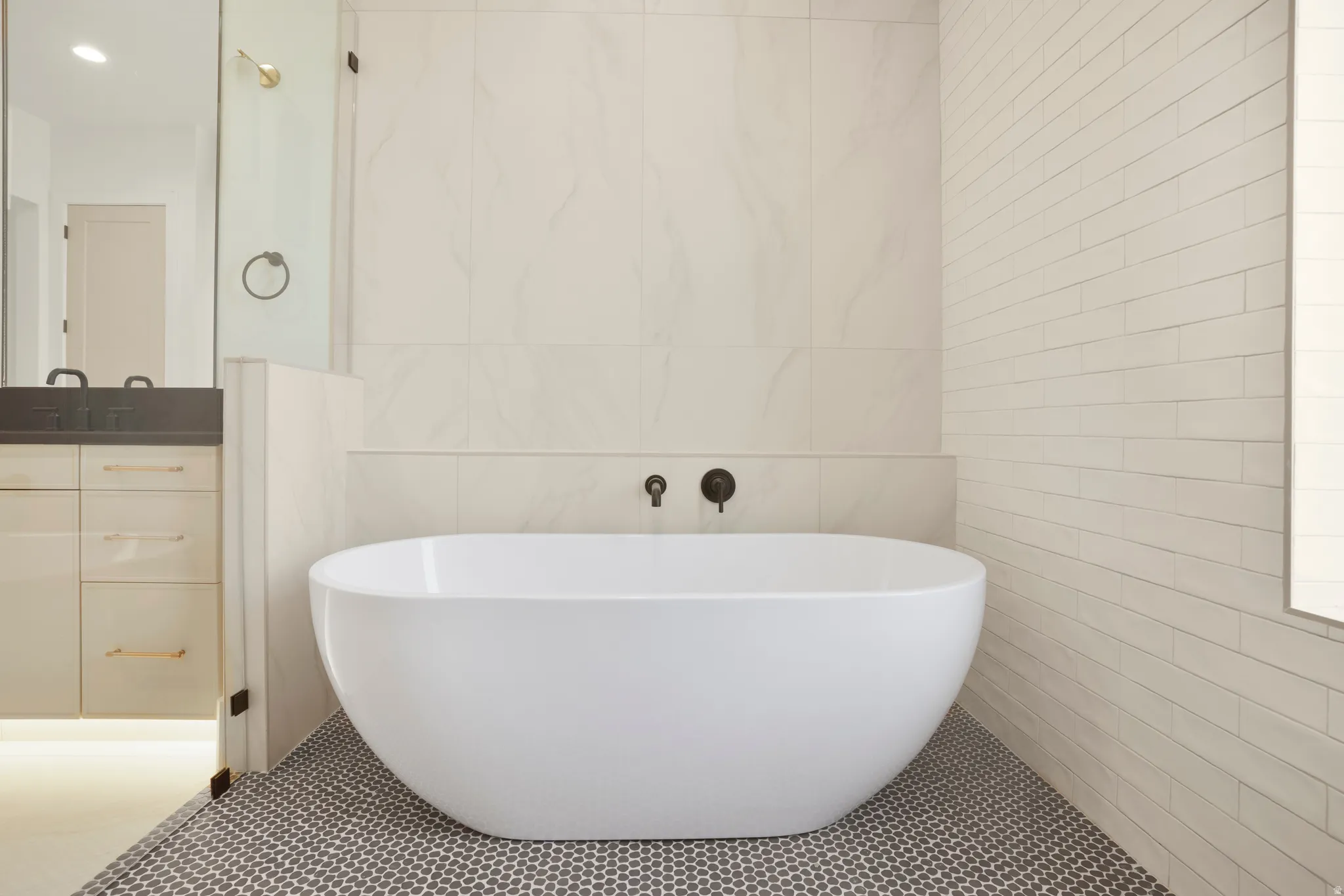 Freestanding soaking tub with matte black wall-mounted fixtures