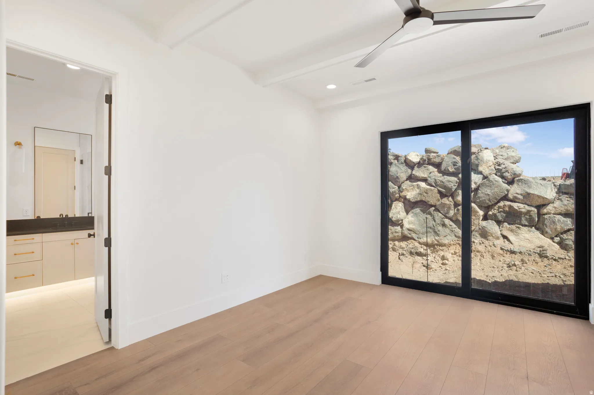 Spacious room featuring wood-finish flooring, a contemporary ceiling fan, and recessed lighting