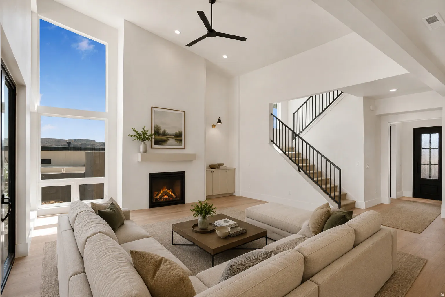 Spacious living area featuring a soaring vaulted ceiling, large picture windows, a modern fireplace with mantel, recessed lighting, and wood-finish flooring
