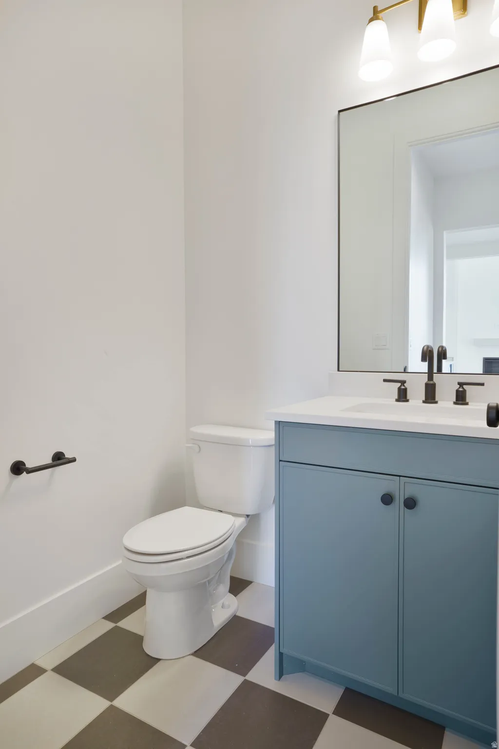 Powder room featuring a blue vanity with a white countertop, large rectangular mirror, and checkered floor