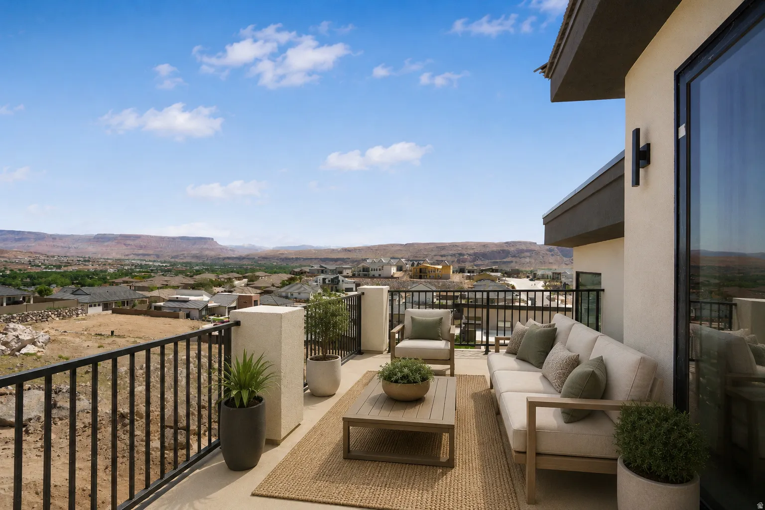Outdoor terrace featuring a stucco exterior, dark railing, and expansive mountain scenery