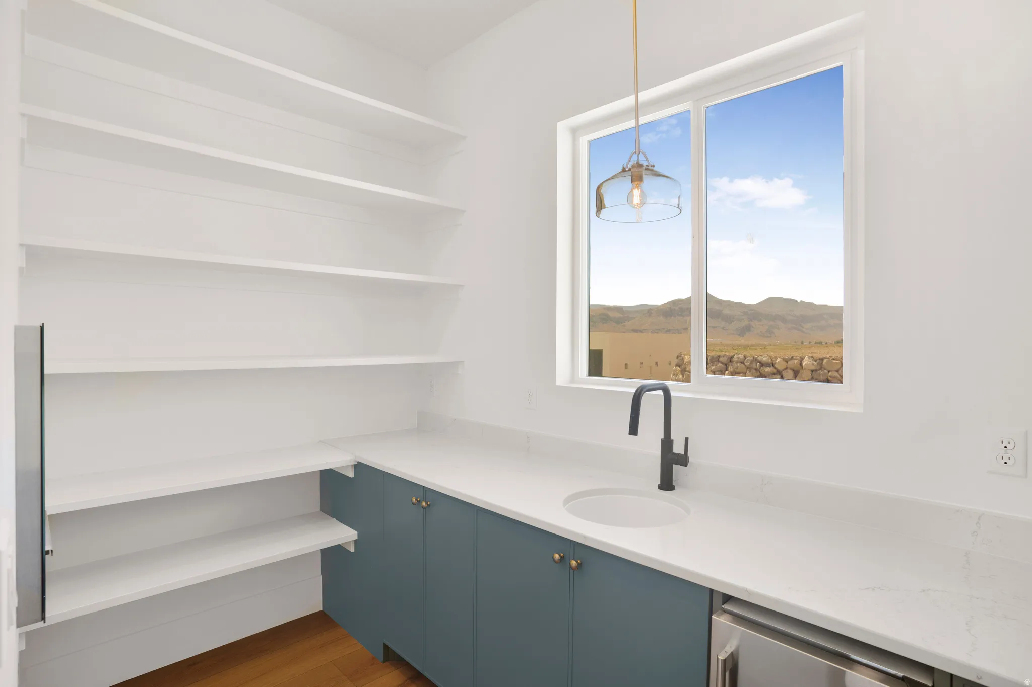 Built-in shelving and cabinetry with quartz countertops complement a window overlooking a mountainous landscape
