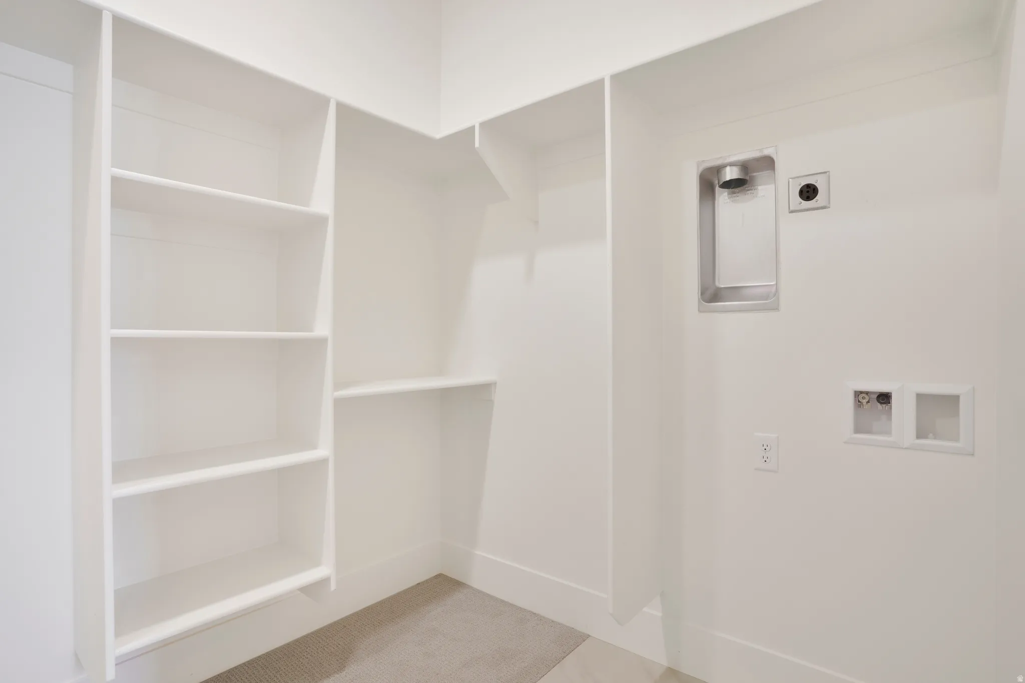 Dedicated laundry area featuring a stainless steel utility sink, electrical outlet, and plumbing hookups