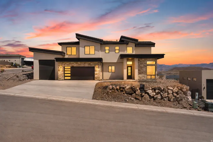 Modern architectural residence featuring a prominent two-car garage with horizontal glass inserts, additional single-car garage, and a concrete driveway