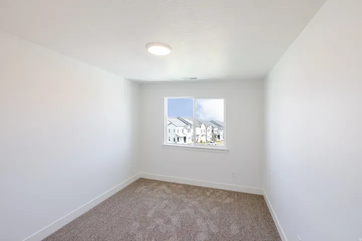 Neutral wall paint, textured carpet flooring, single window, and flush-mount ceiling light