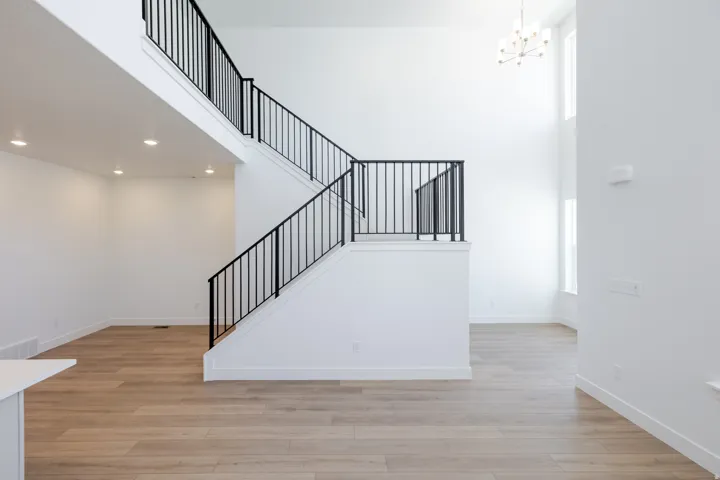 Two-story interior with wood-finish flooring, recessed lighting, and a modern chandelier