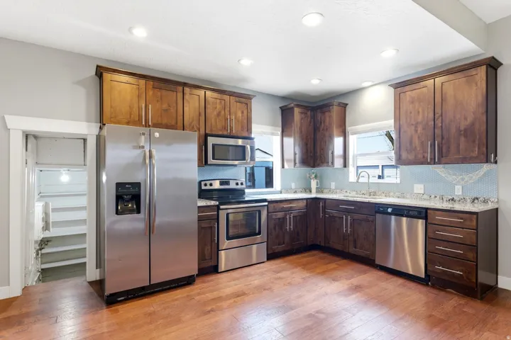 Modern kitchen featuring wood-finish flooring, recessed lighting, and stainless steel appliances