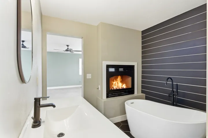 Freestanding soaking tub with floor-mounted faucet, complemented by a built-in fireplace