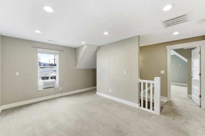 Upper-level room with recessed ceiling lighting, textured carpeting, and a window
