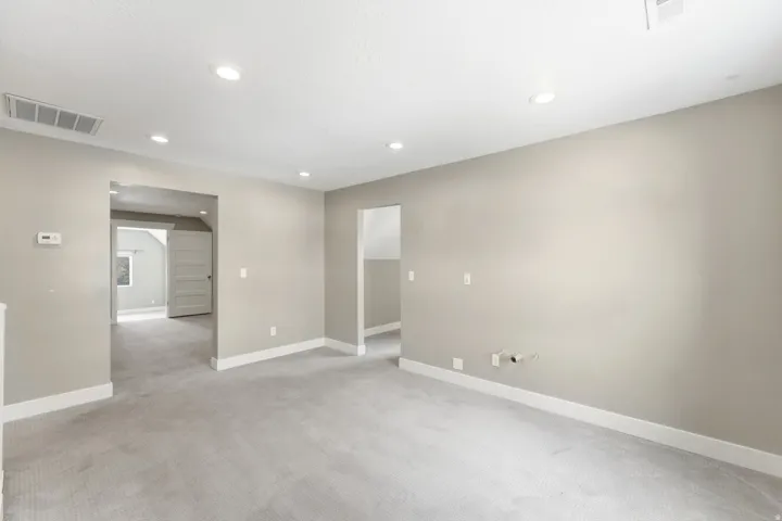 Spacious room featuring light gray carpeting, recessed lighting, and ample wall space