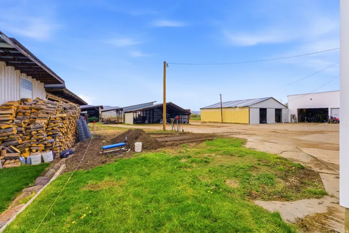 Multiple outbuildings featuring corrugated metal roofs, various siding materials, and concrete/gravel driveways