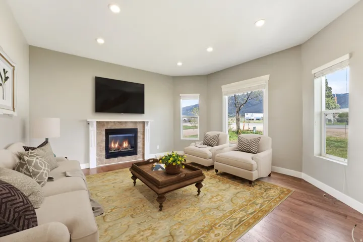 Spacious living area featuring a built-in fireplace with a tile surround and mantel, recessed lighting, and wood-finish flooring