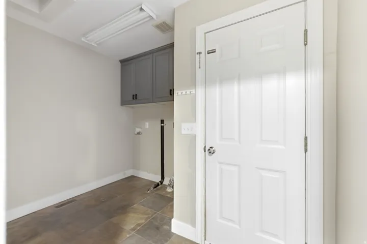 Dedicated utility space featuring overhead gray cabinetry, durable tile flooring, and integrated laundry hookups