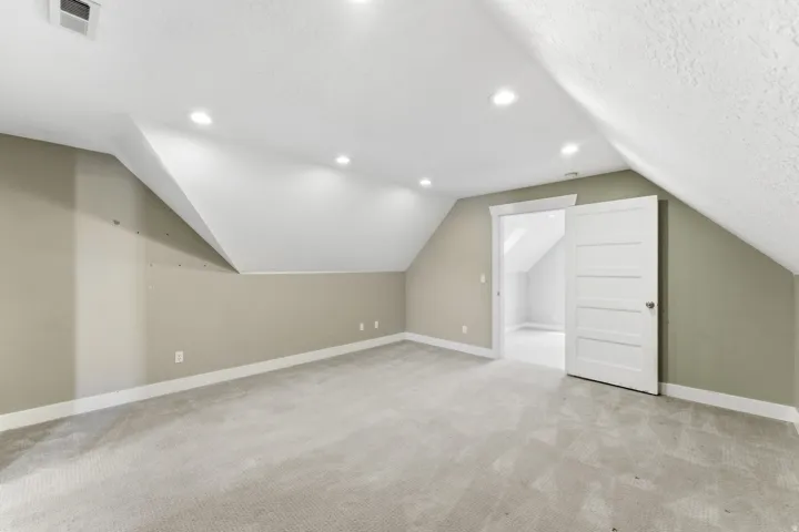 Carpeted room featuring a neutral color palette, recessed lighting, white baseboards, and a paneled interior door