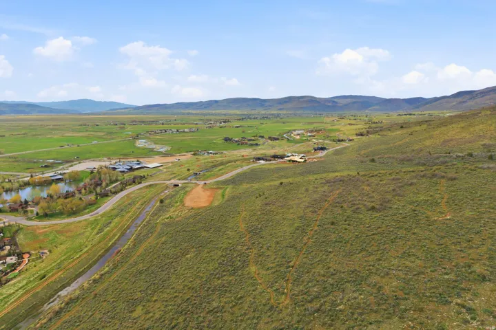 Expansive land parcel featuring varied topography, distant mountains, and a significant pond feature