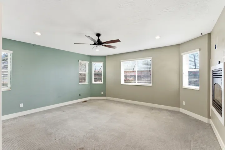 Carpeted room featuring multiple windows with blinds, a ceiling fan, recessed lighting, and a built-in fireplace