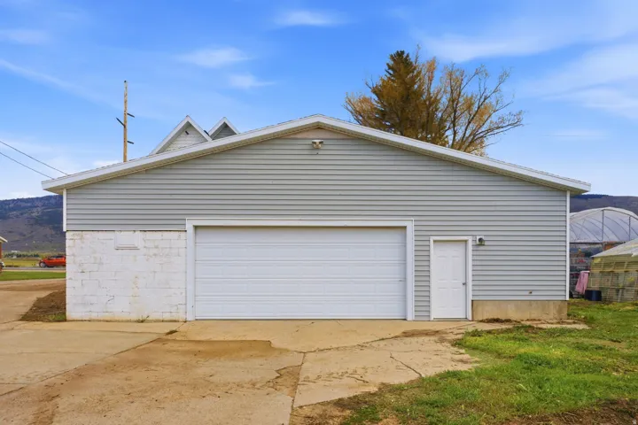 Detached garage featuring a white overhead door and a separate entry door