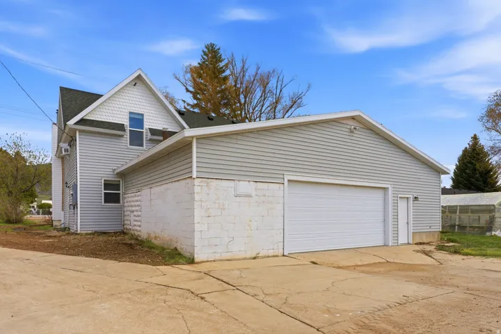 Detached two-car garage with a white overhead door and a pedestrian entrance, featuring horizontal siding