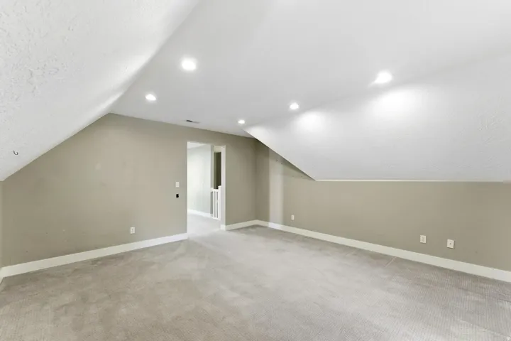 Carpeted room with recessed lighting and a sloped ceiling