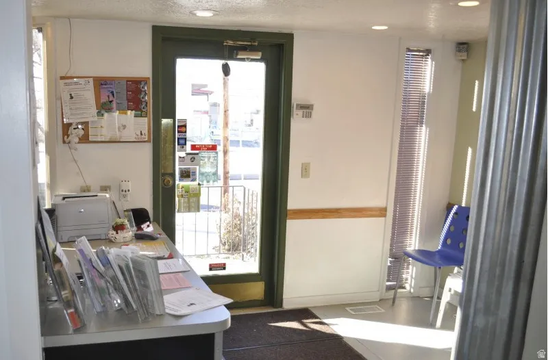 Entry area featuring a glass-paneled door with a dark frame, a cork board, and a built-in counter surface