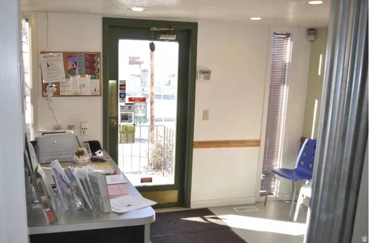 Entry area featuring a glass-paneled door with a dark frame, a cork board, and a built-in counter surface