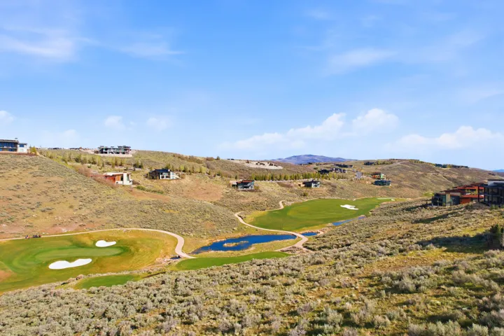 Expansive hillside property featuring a golf course, multiple greens, and a water feature