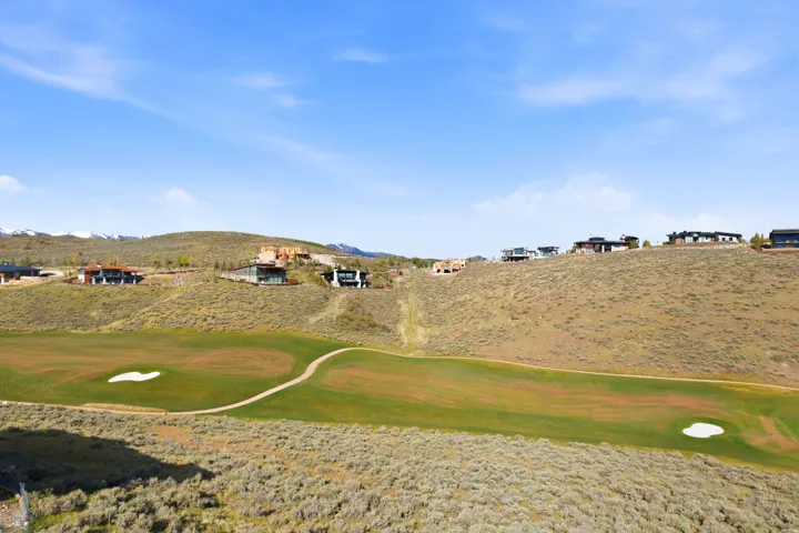 Expansive golf course terrain featuring green fairways, sand traps, and a paved cart path