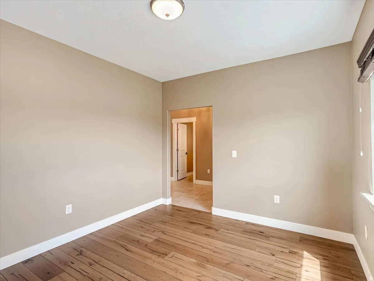 Spacious room featuring wood-finish flooring, neutral-toned walls, white baseboards, and a semi-flush mount ceiling light fixture