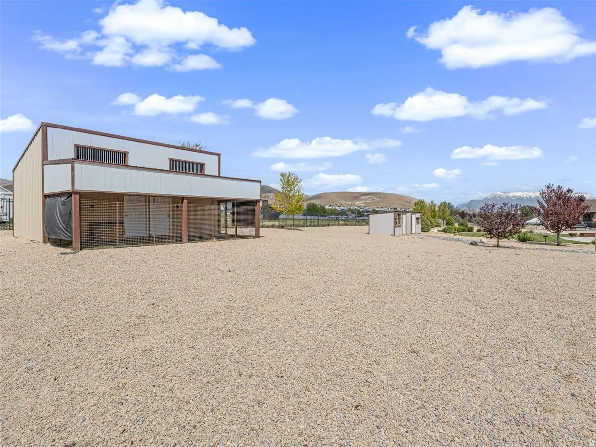 Expansive outdoor space featuring a large gravel surface, a two-story outbuilding with a sheltered ground level, and distant mountain scenery