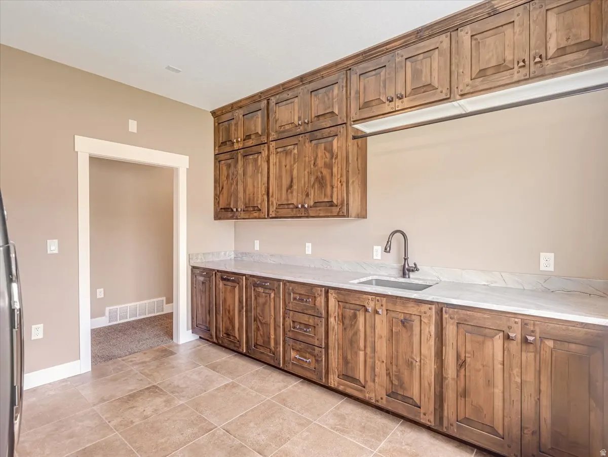 Extensive wood cabinetry with integrated sink, light-toned countertops, and tiled flooring