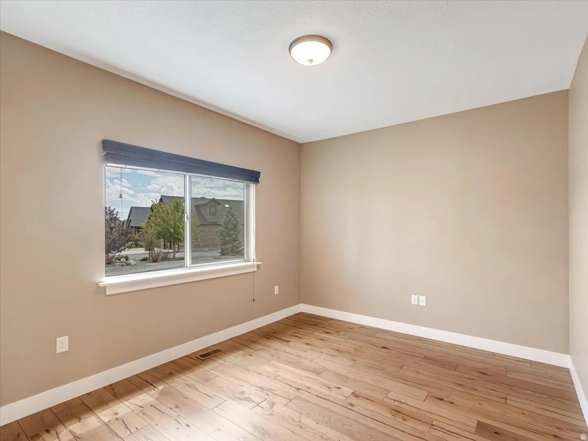 Spacious room featuring wood-finish flooring, neutral-toned walls, and white baseboards