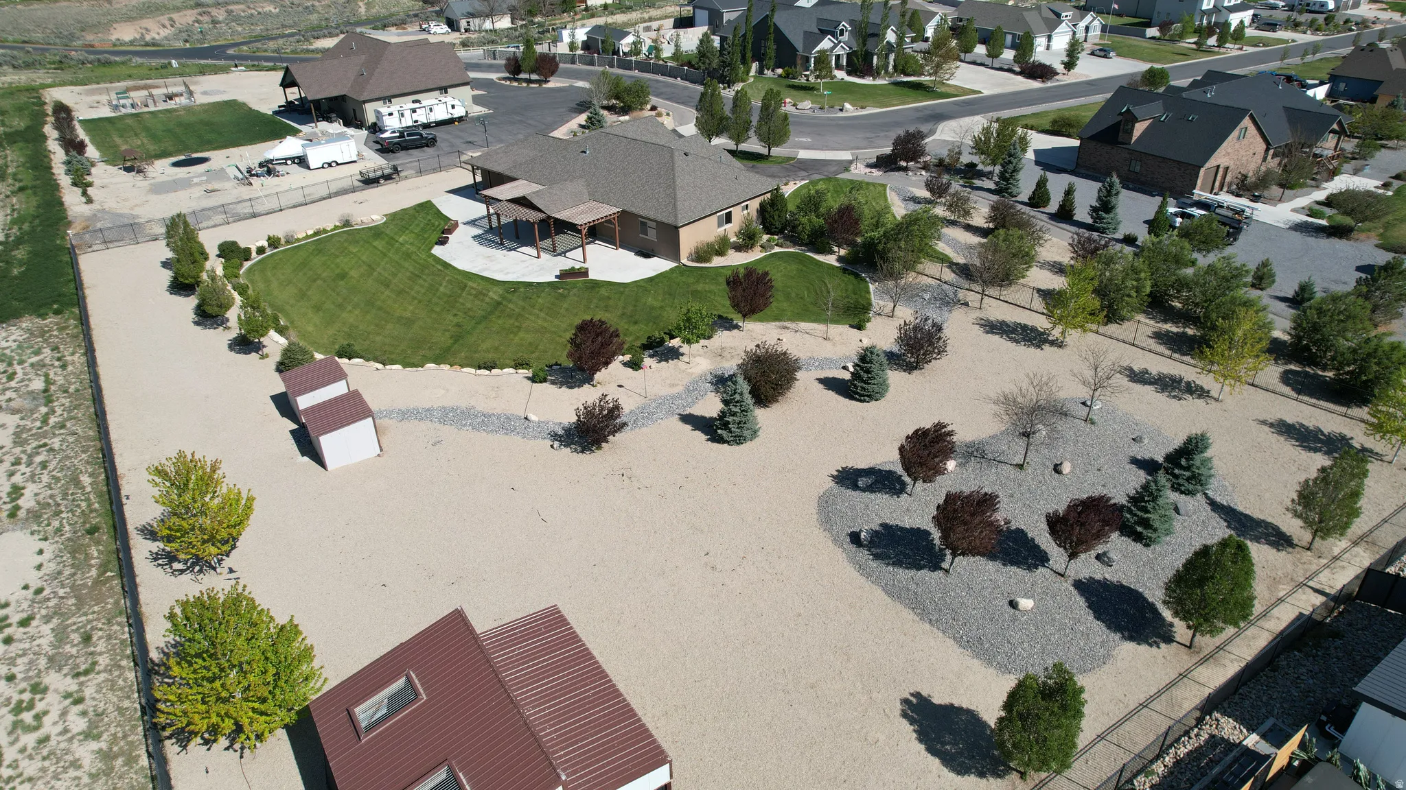 Expansive exterior featuring a large gravel lot, a manicured lawn, and multiple mature trees