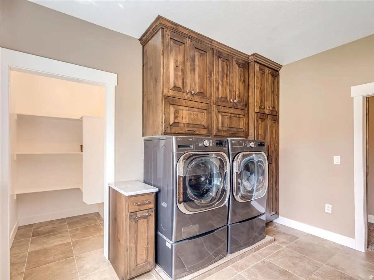 Laundry room featuring tiled flooring and extensive wood-finish cabinetry
